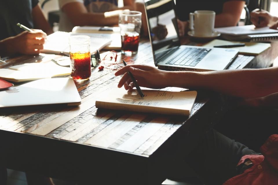 Personas reunidas alrededor de una mesa de trabajo con portatiles y bebidas