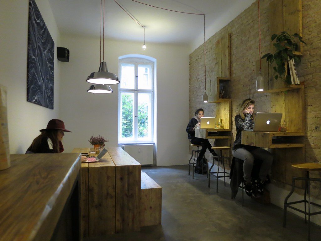 Cafeteria luminosa con varias personas trabajando con portatiles