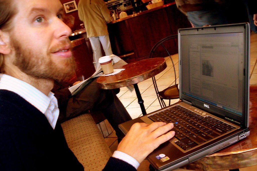 Hombre trabajando con un portatil en una cafeteria