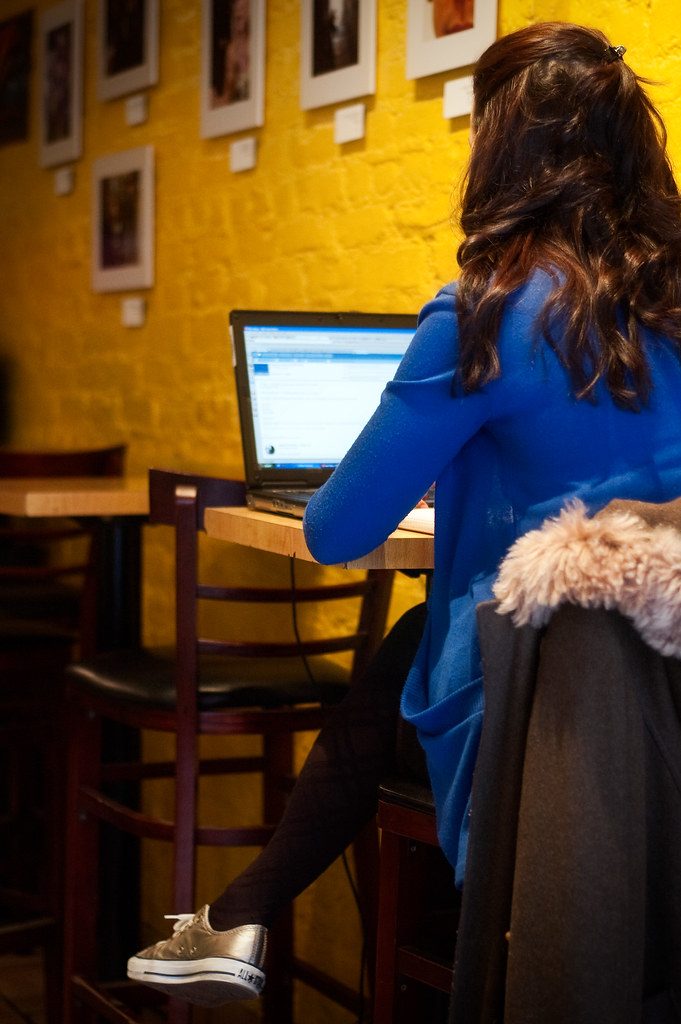 Mujer trabajando con un portatil en una cafeteria de luz calida