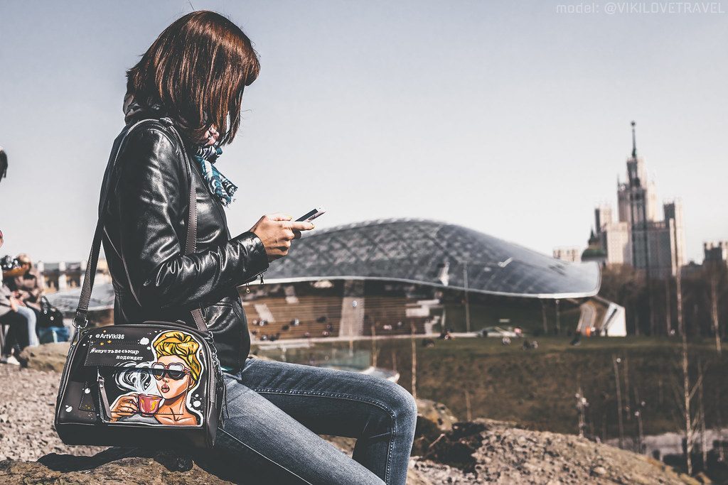 Mujer sentada al aire libre escribiendo un mensaje en el movil